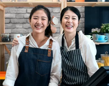 Two women stand at the cash register of a small business