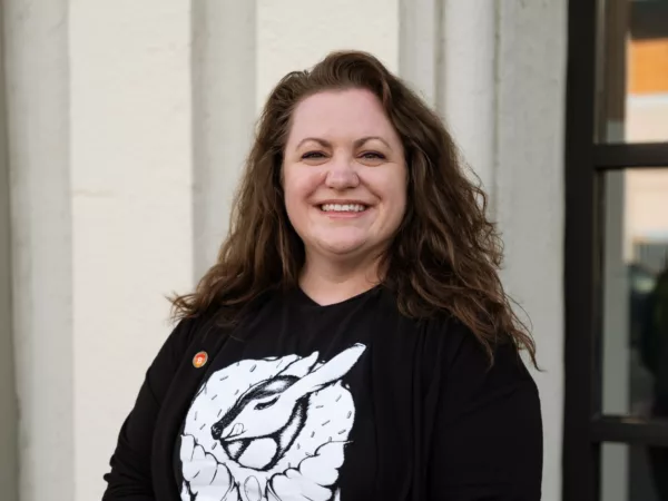 Katie Taylor, pictured outside the Beneficial State Bank Oakland branch. She is smiling at the camera and wearing a Beneficial State Bank pin.