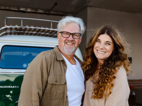 Merlin and Marcia, owners of Dogeared Do Good Bus, stand in front of a bus outside