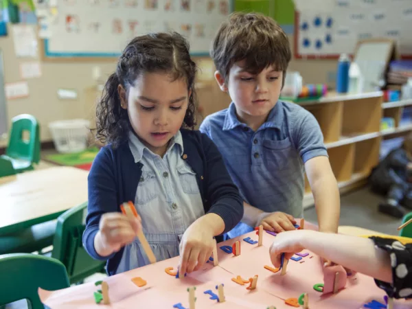 Two preschool children working on a craft in a classroom