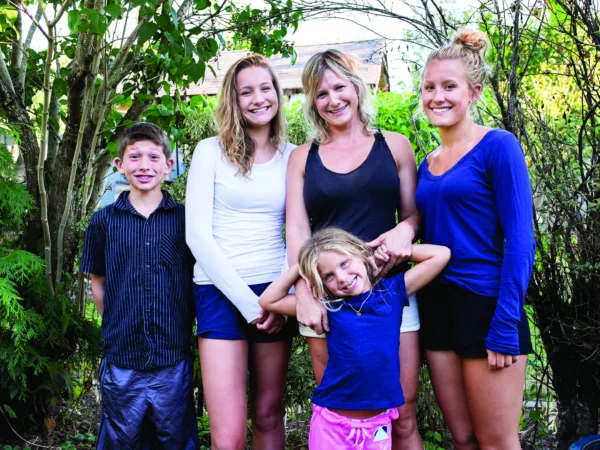 A family of five stands together, smiling