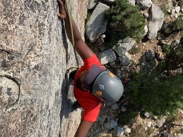 GirlVentures on the rise - a girl photographed from above as she climbs up the side of a sheer rock